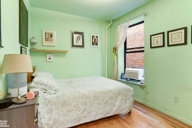 bedroom with baseboards, wood finished floors, and cooling unit