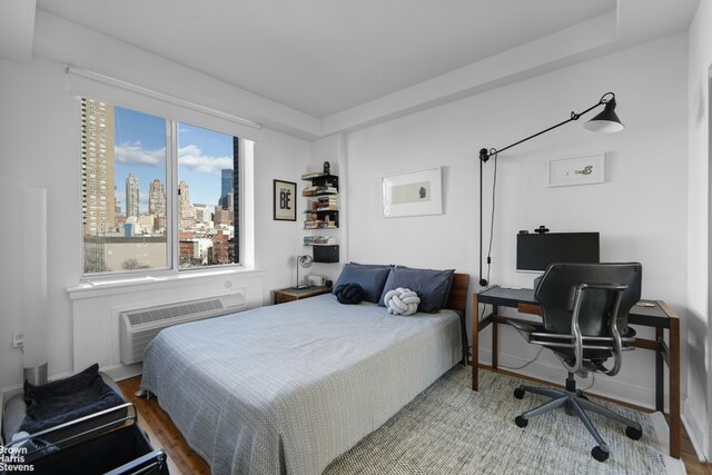 bedroom featuring hardwood / wood-style flooring and an AC wall unit