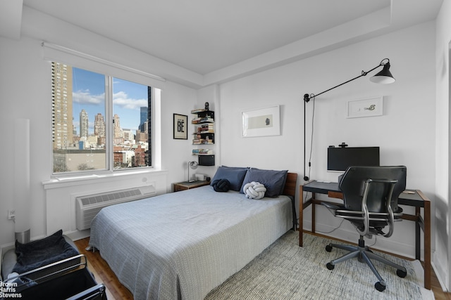 bedroom with a wall mounted air conditioner and wood finished floors