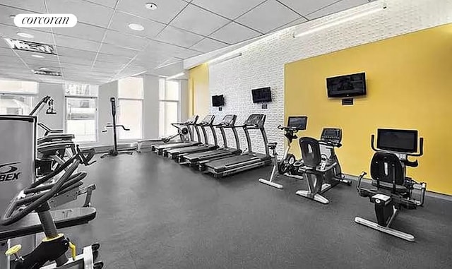 exercise room with visible vents, a drop ceiling, and baseboards