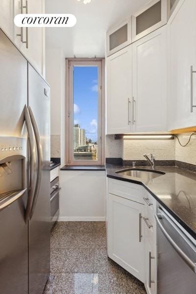 kitchen with baseboards, granite finish floor, a sink, white cabinets, and appliances with stainless steel finishes