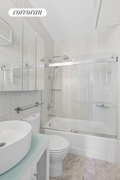 full bath featuring enclosed tub / shower combo, toilet, and vanity