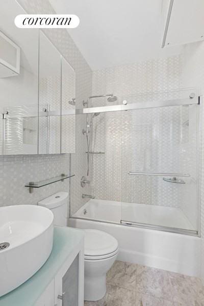 full bathroom featuring bath / shower combo with glass door, toilet, marble finish floor, and vanity