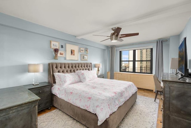 bedroom featuring a ceiling fan, light wood finished floors, and beamed ceiling