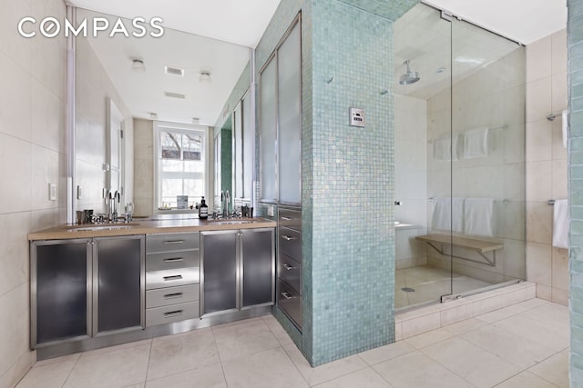 bathroom with a stall shower, tile walls, and a sink