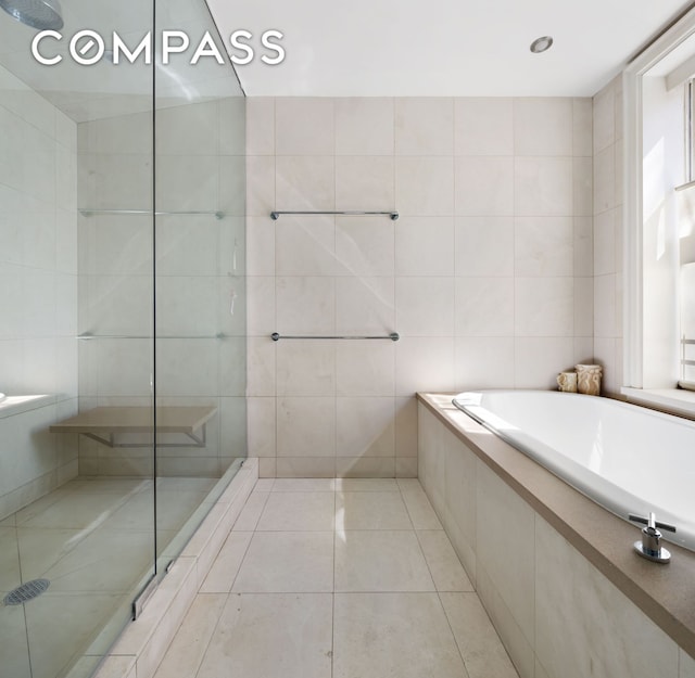 bathroom featuring tile patterned flooring, tile walls, a garden tub, and tiled shower