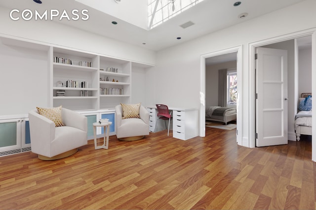 sitting room with visible vents, a skylight, and wood finished floors