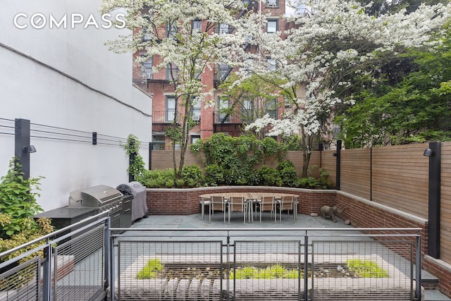 view of patio with outdoor dining area, fence, and a grill