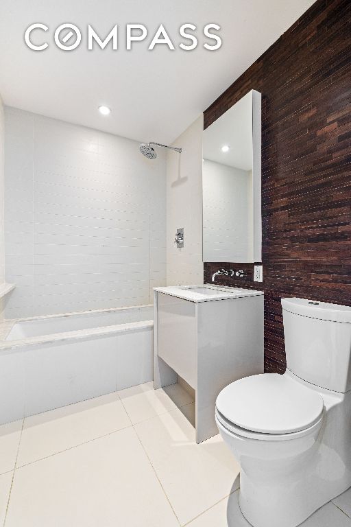 bathroom with wooden walls, toilet, tile patterned flooring, vanity, and shower / washtub combination