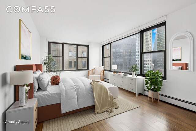 bedroom with hardwood / wood-style flooring and a baseboard heating unit