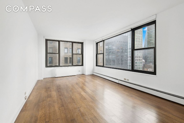 spare room with a baseboard radiator and wood-type flooring