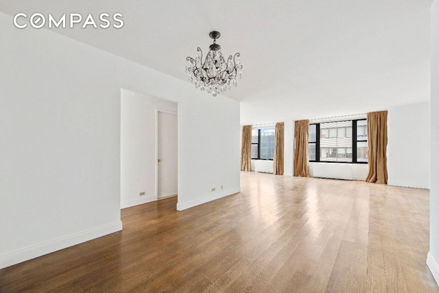 unfurnished room with hardwood / wood-style flooring and a chandelier