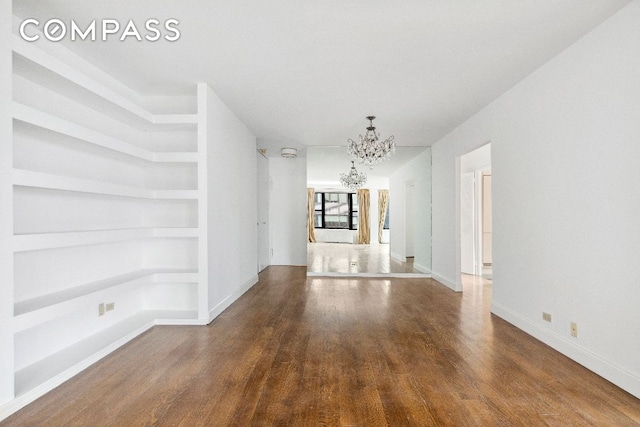 unfurnished living room featuring an inviting chandelier, hardwood / wood-style floors, and built in features