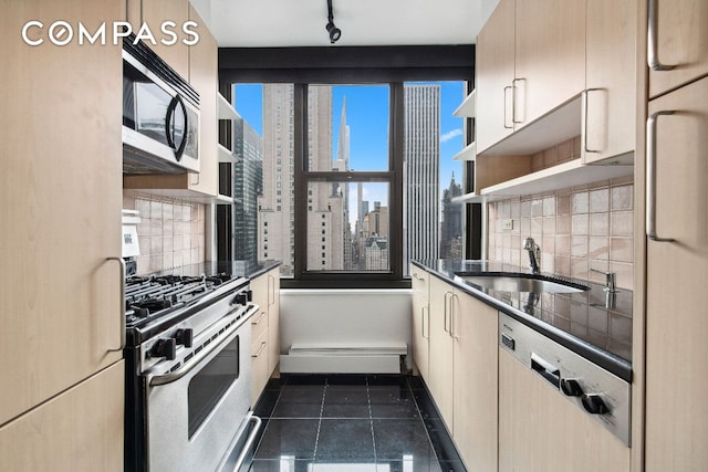 kitchen featuring tasteful backsplash, sink, dark tile patterned flooring, and appliances with stainless steel finishes