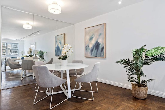 dining space featuring dark parquet flooring and track lighting