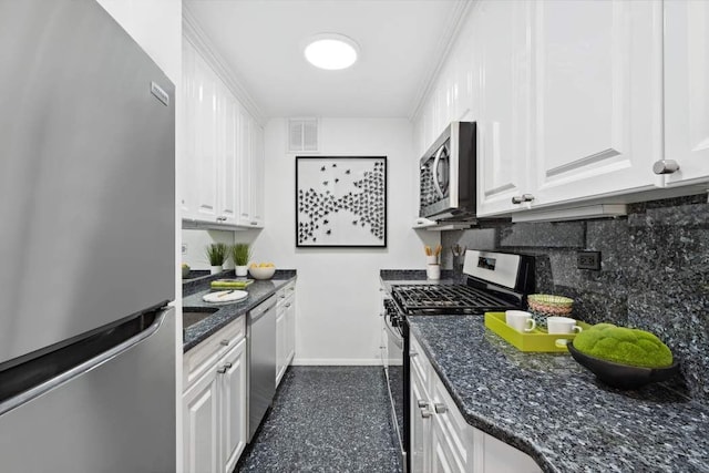 kitchen with dark stone countertops, backsplash, white cabinets, and appliances with stainless steel finishes