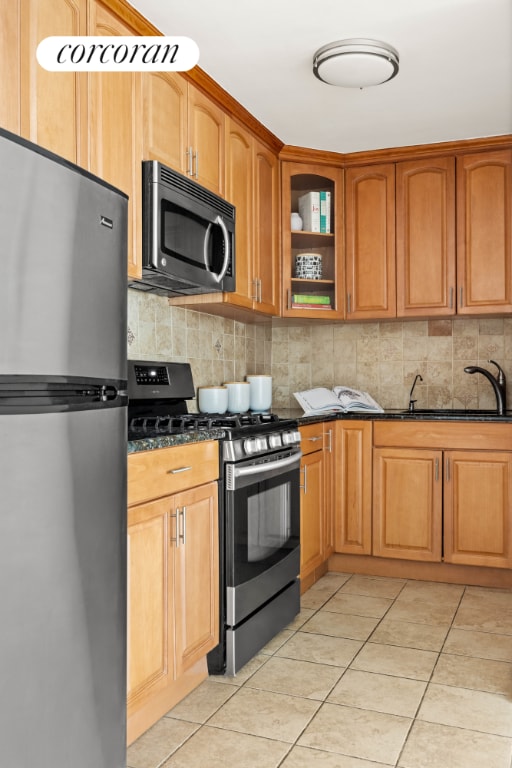 kitchen with backsplash, stainless steel appliances, sink, and dark stone counters