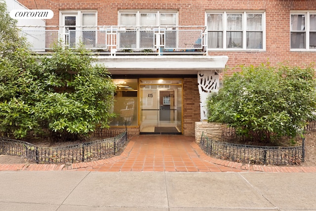 entrance to property featuring brick siding and a balcony