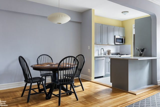 kitchen featuring appliances with stainless steel finishes, pendant lighting, sink, gray cabinetry, and backsplash