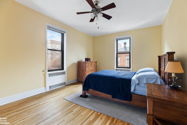 bedroom with multiple windows, radiator, ceiling fan, and light hardwood / wood-style flooring