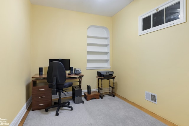 office with built in shelves and light colored carpet