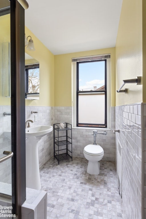 bathroom featuring tile walls and toilet