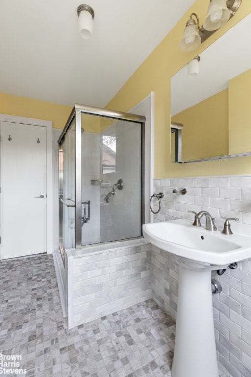 bathroom featuring an enclosed shower, sink, and tile walls