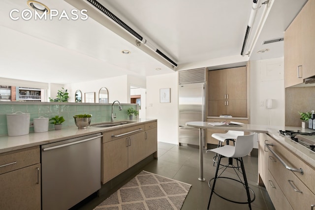 kitchen with visible vents, dark tile patterned flooring, a sink, stainless steel appliances, and tasteful backsplash