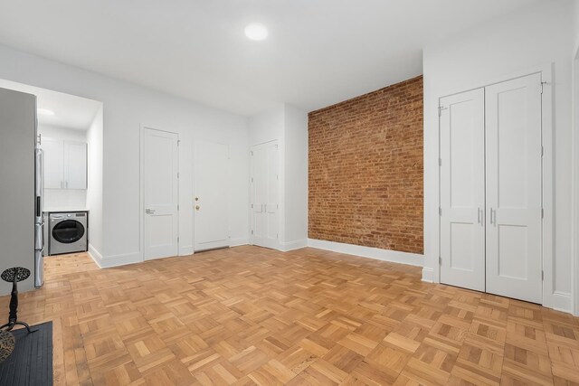 interior space featuring brick wall, washer / dryer, and light parquet floors