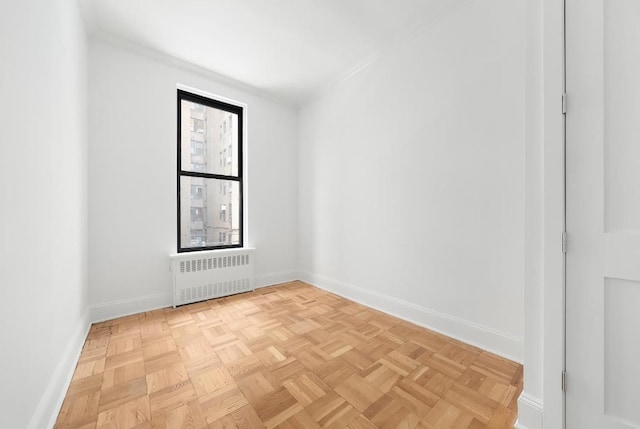 empty room featuring radiator heating unit and light parquet flooring