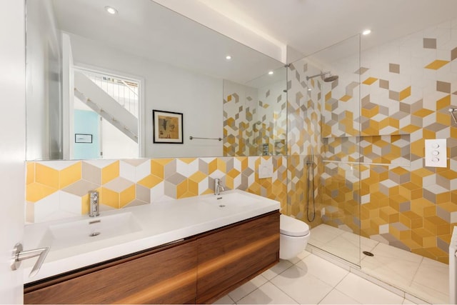 bathroom featuring tiled shower, toilet, tile walls, vanity, and tile patterned flooring