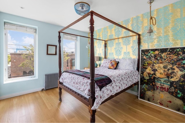 bedroom with multiple windows, radiator, and hardwood / wood-style floors