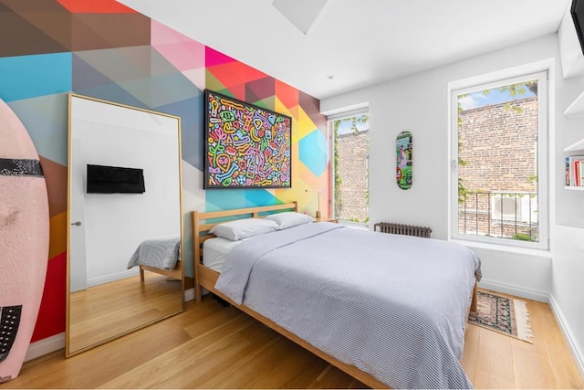 bedroom with multiple windows, radiator, and hardwood / wood-style floors