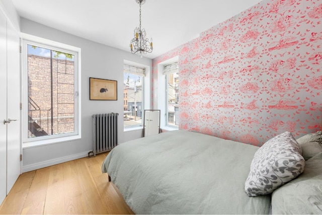 bedroom featuring an inviting chandelier, radiator, and light wood-type flooring