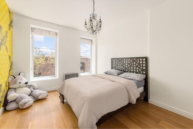 bedroom with an inviting chandelier, radiator heating unit, and light hardwood / wood-style flooring