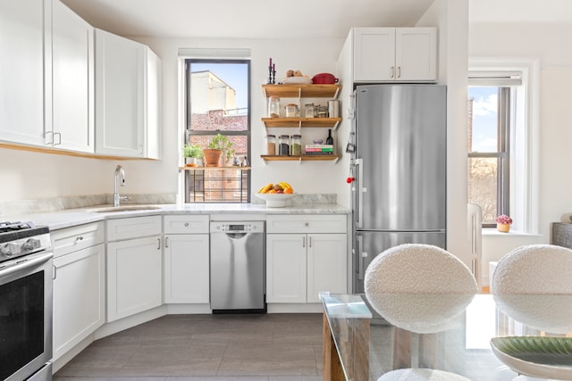 kitchen with stainless steel appliances, white cabinetry, plenty of natural light, and sink