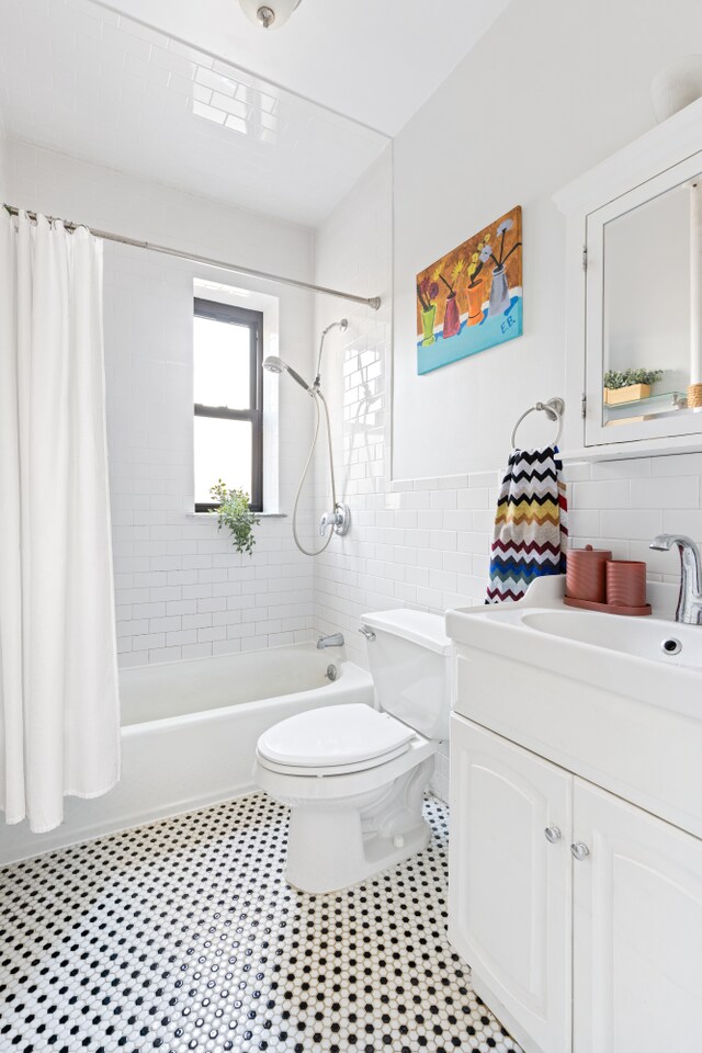 full bathroom with tile walls, vanity, toilet, and shower / bath combo with shower curtain