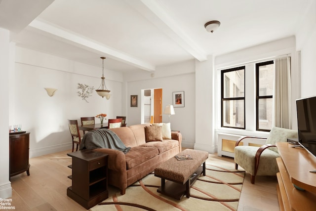 living area featuring beamed ceiling, baseboards, and light wood finished floors