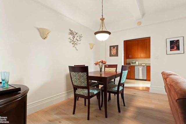 dining room featuring light wood finished floors, baseboards, and beam ceiling