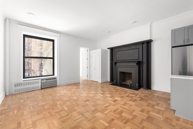 unfurnished living room with light parquet floors, crown molding, and radiator