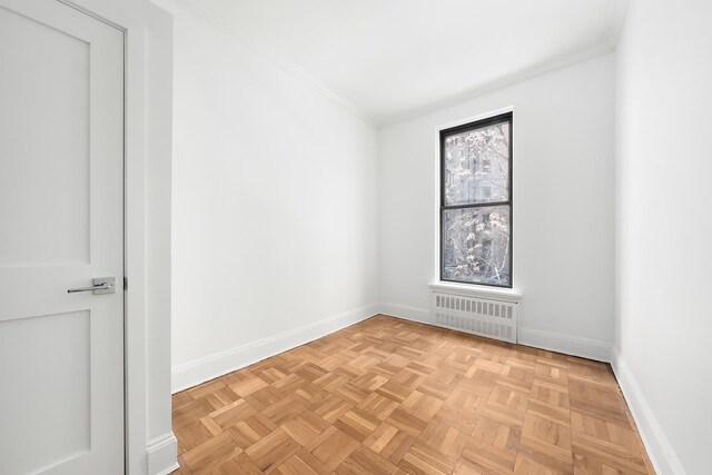 empty room with light parquet flooring and radiator heating unit