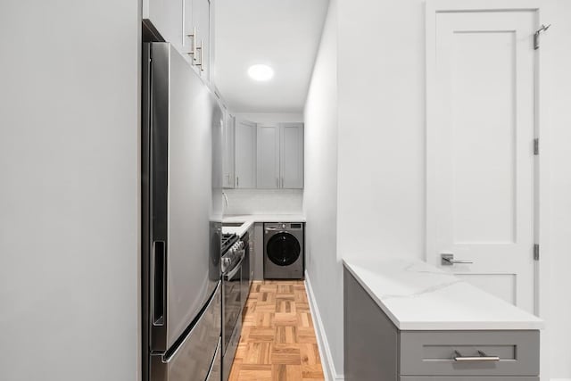 clothes washing area with separate washer and dryer and light parquet floors