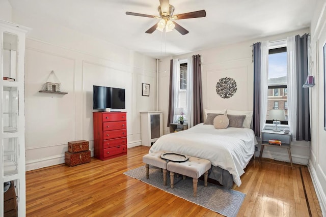 bedroom featuring a ceiling fan, a decorative wall, and wood finished floors