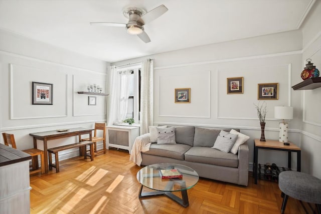 living area with ceiling fan, radiator heating unit, and a decorative wall