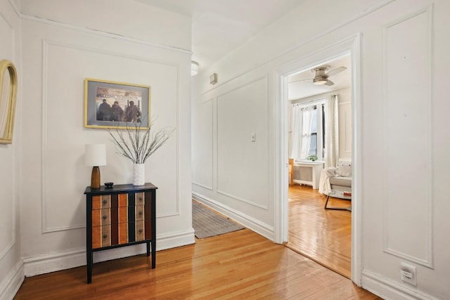 hallway with wood finished floors and a decorative wall