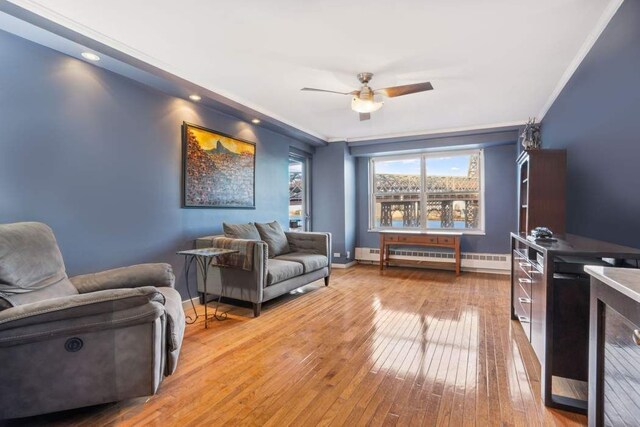 living room featuring crown molding, ceiling fan, and light wood-type flooring