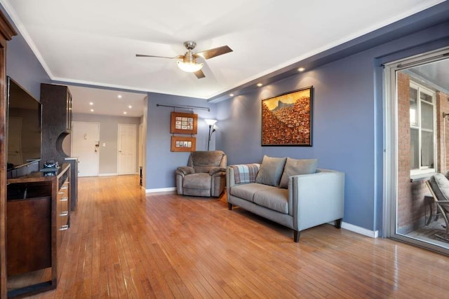 living room featuring crown molding, light hardwood / wood-style flooring, and ceiling fan