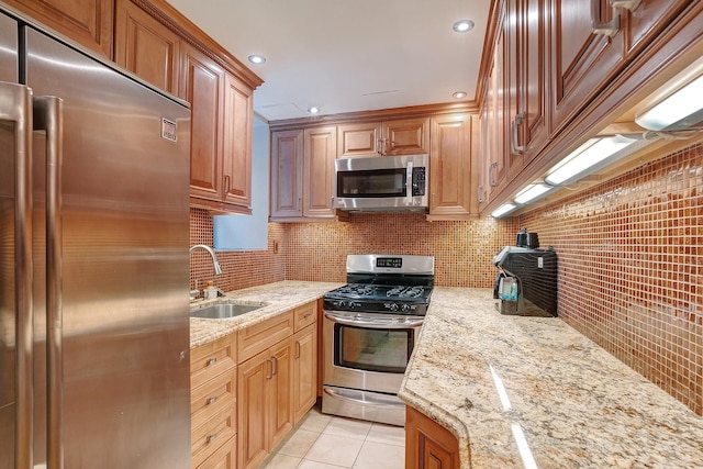 kitchen featuring light stone counters, light tile patterned floors, backsplash, appliances with stainless steel finishes, and a sink