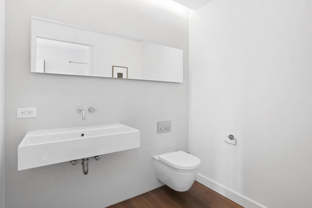 bathroom with toilet, baseboards, and wood finished floors