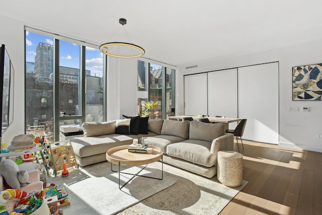 living room with floor to ceiling windows, visible vents, and wood finished floors